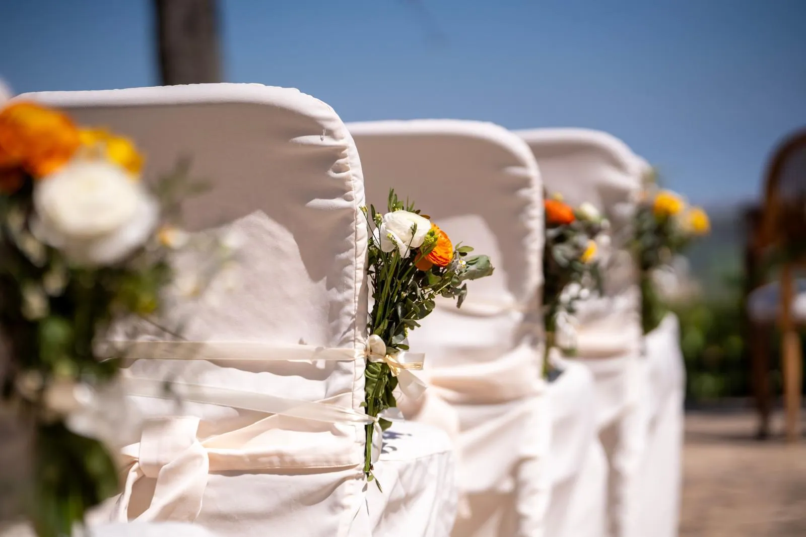 Weiße Stuhlhussen mit Blumen bei einer freien Trauung im Freien